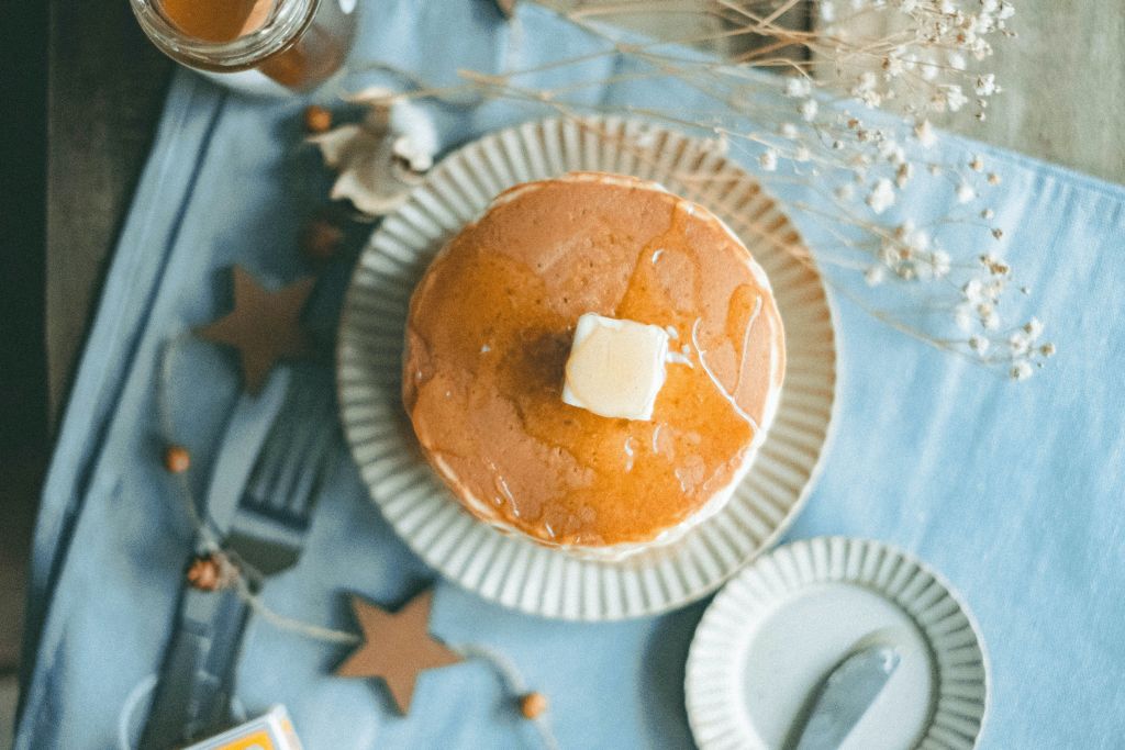 Pancakes topped with maple syrup and butter cubes